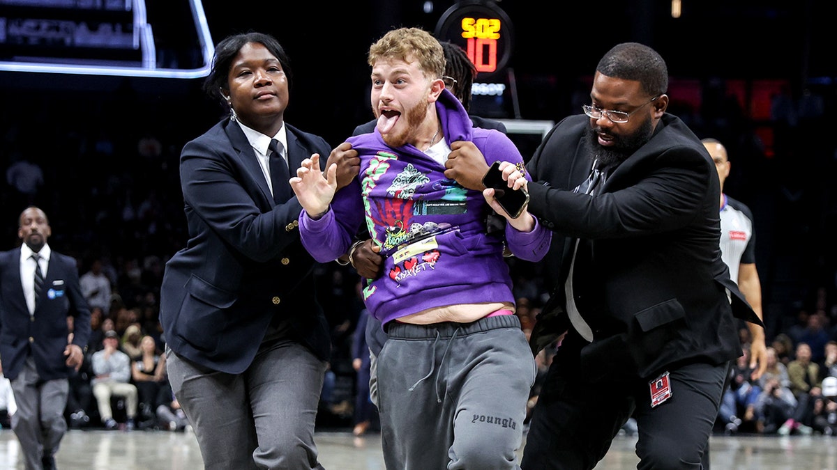 A fan is taken off the court