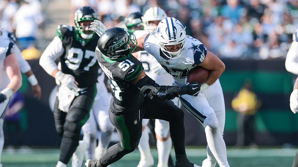 Jake Ferguson stiff arms a defender