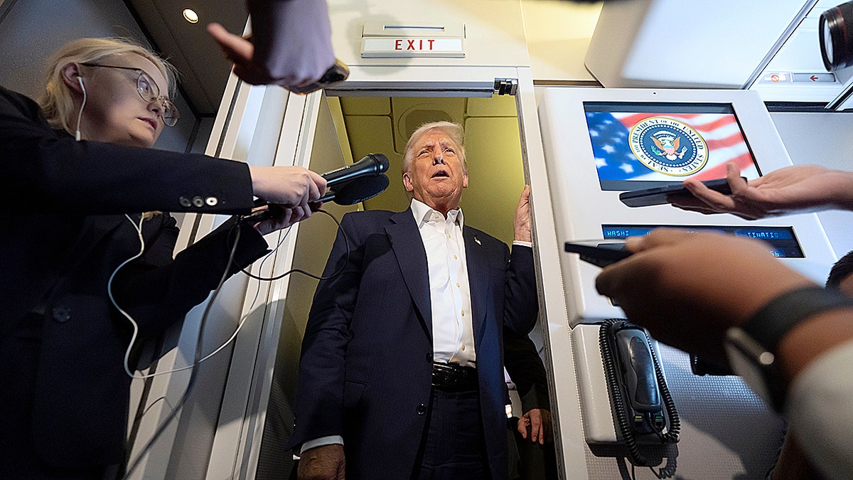 President Donald Trump talking to reporters on Air Force One on his way to Japan