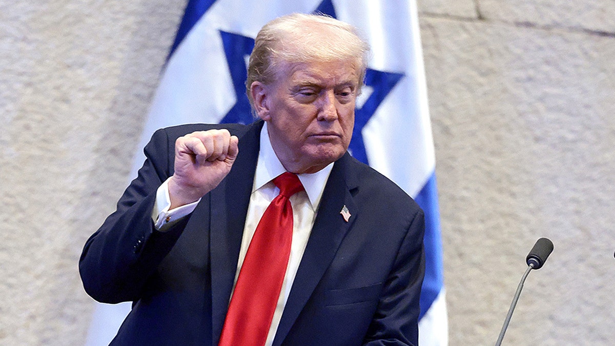 President Donald Trump raises his fist while speaking to Israel's parliament