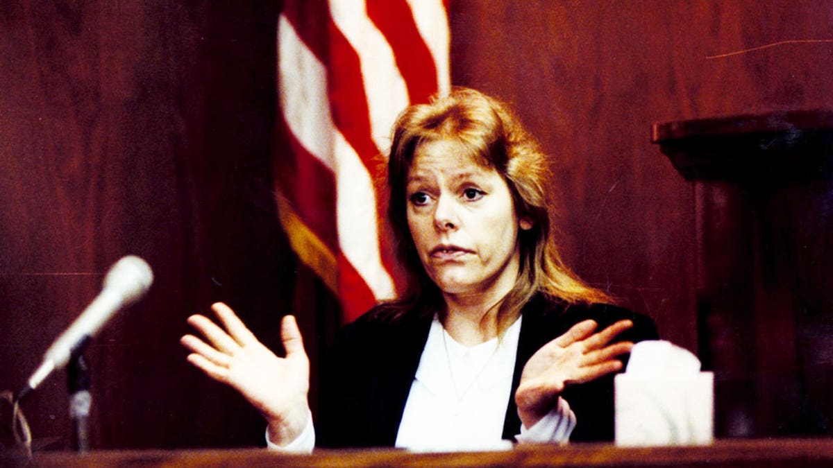 Aileen Wuornos sitting in front of an American flag as she testifies during her murder trial.