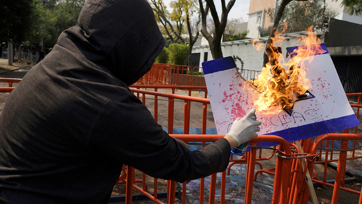 Protester burns poster of Israeli flag outside embassy in Mexico City