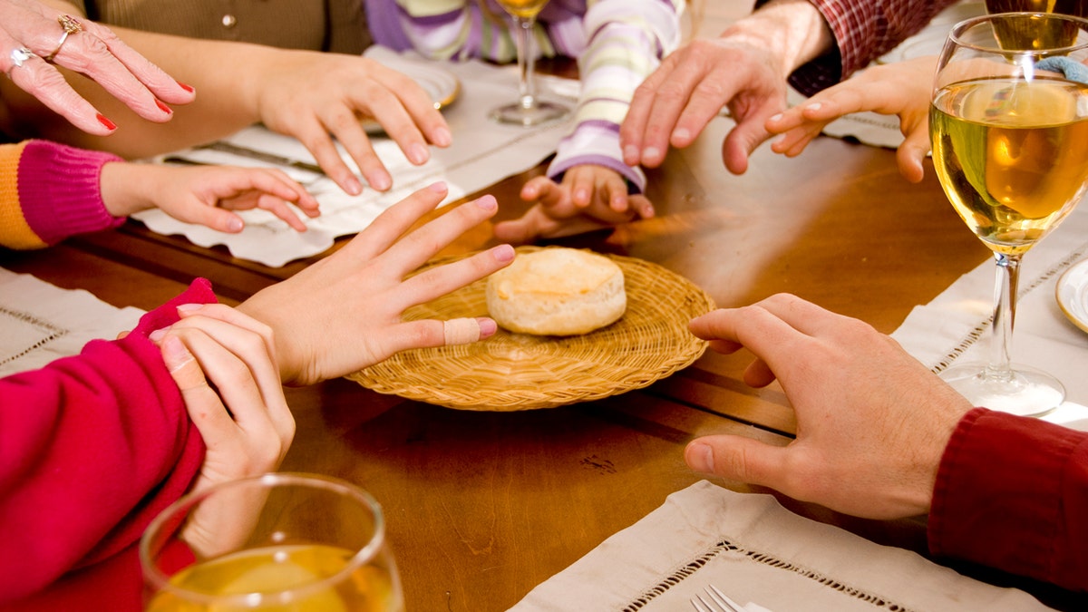 family at dinner table fighting over biscuit hands reaching out to grab