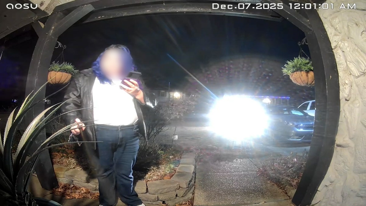 woman with purple hair, leather jacket, and jeans spraying substance from a distance