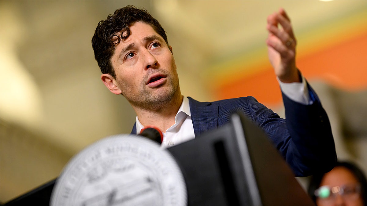 Minneapolis Mayor Jacob Frey speaks at a podium during a press conference inside City Hall.