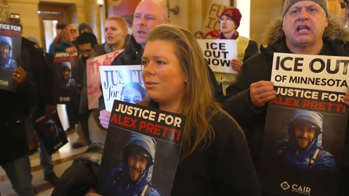 Woman holds "Justice for Alex Pretti" sign amid crowd of protesters.