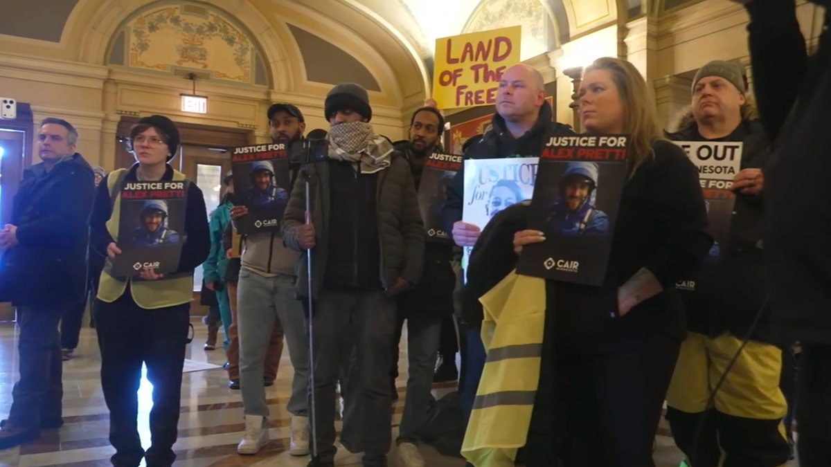 Anti-ICE protesters hold signs.