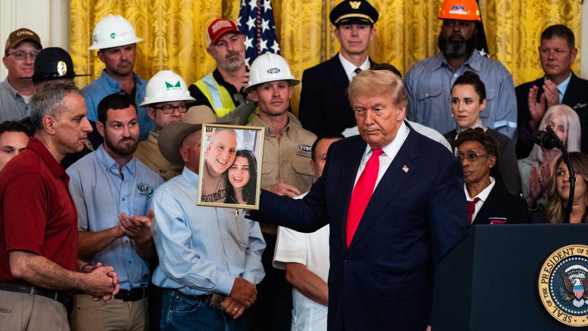 Trump holds up a photo of Katie Abraham.