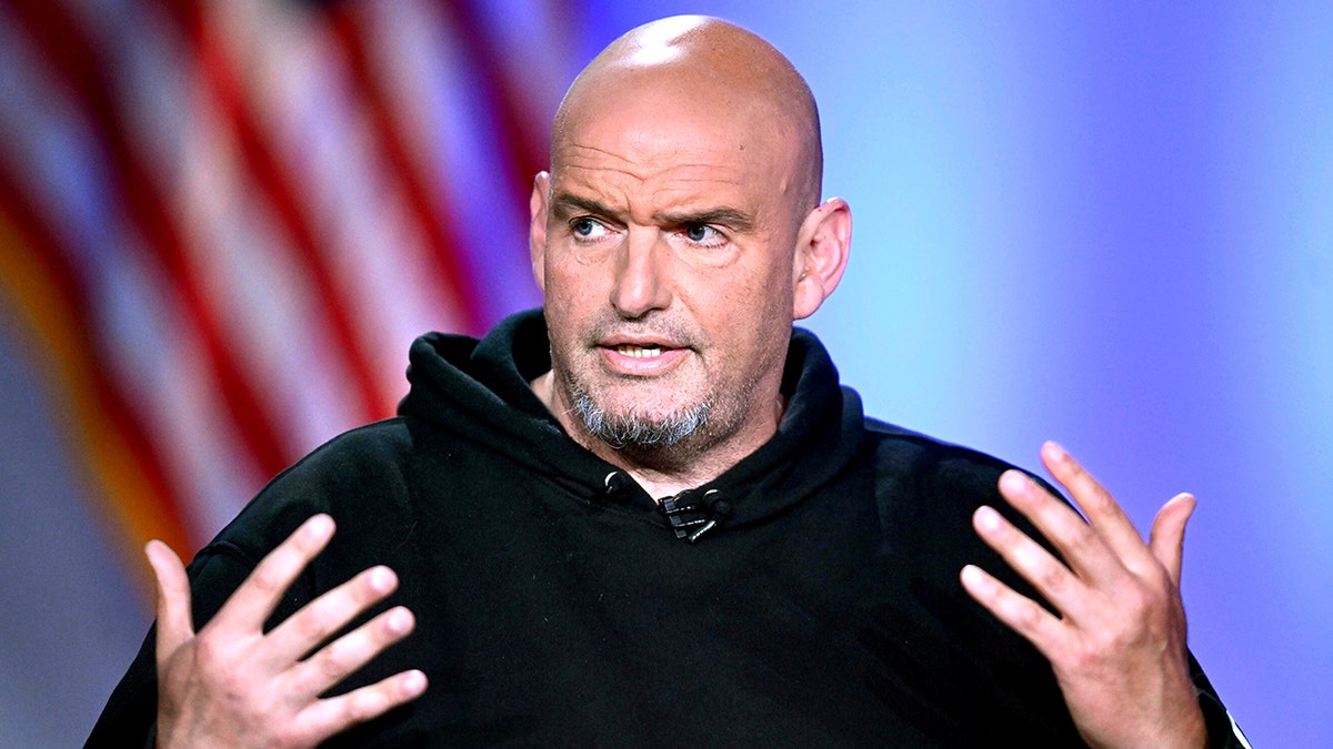 John Fetterman gesturing while wearing back hoodie during a debate