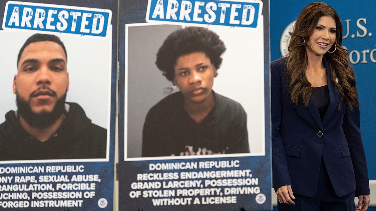 Homeland Security Secretary Kristi Noem walks past posters of suspects taken into custody