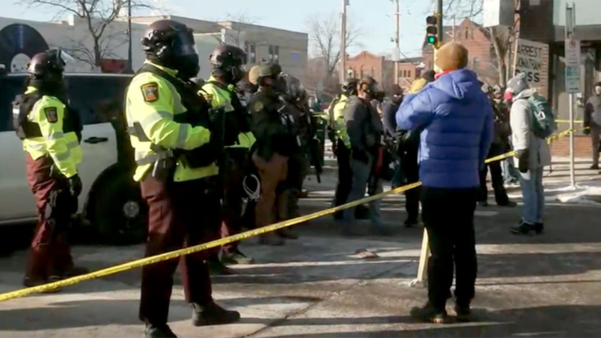 Protesters facing police with crime tape between them