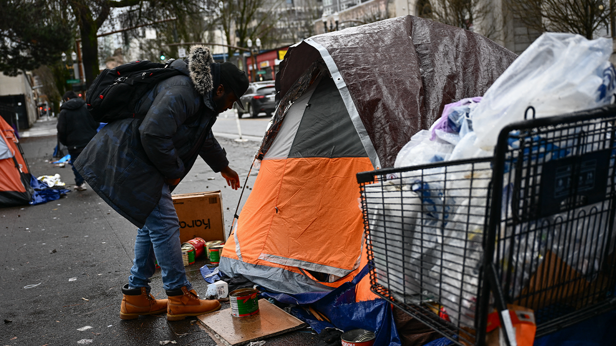 Person stands near tent at homeless encampment in Portland, OR