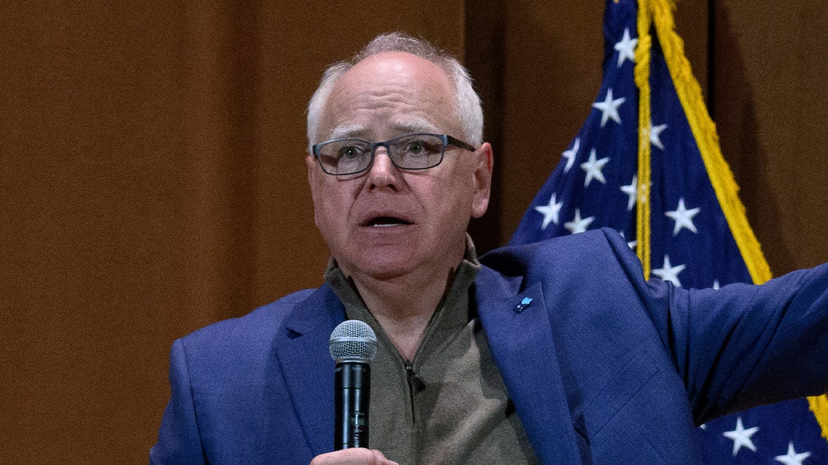 Tim Walz holds a microphone while speaking before a crowd in Ohio