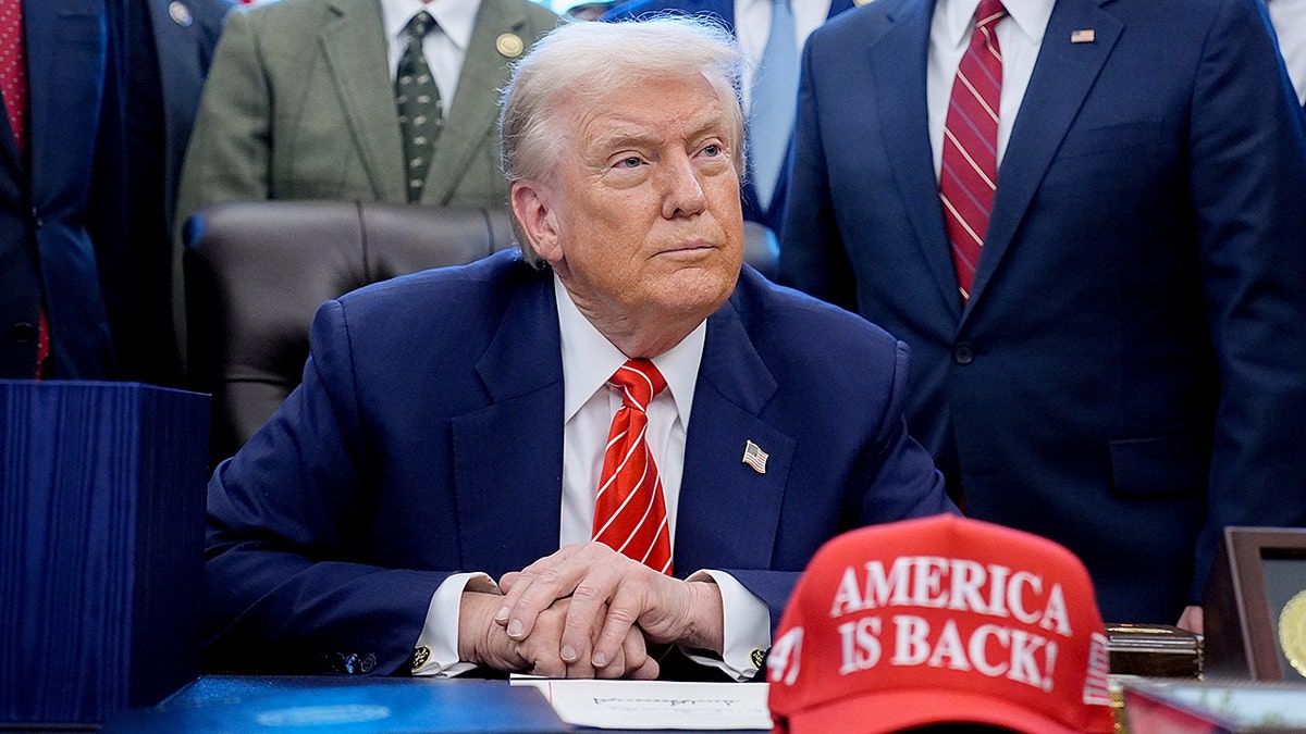 President Trump sits in Oval Office with "America is Back!" hat
