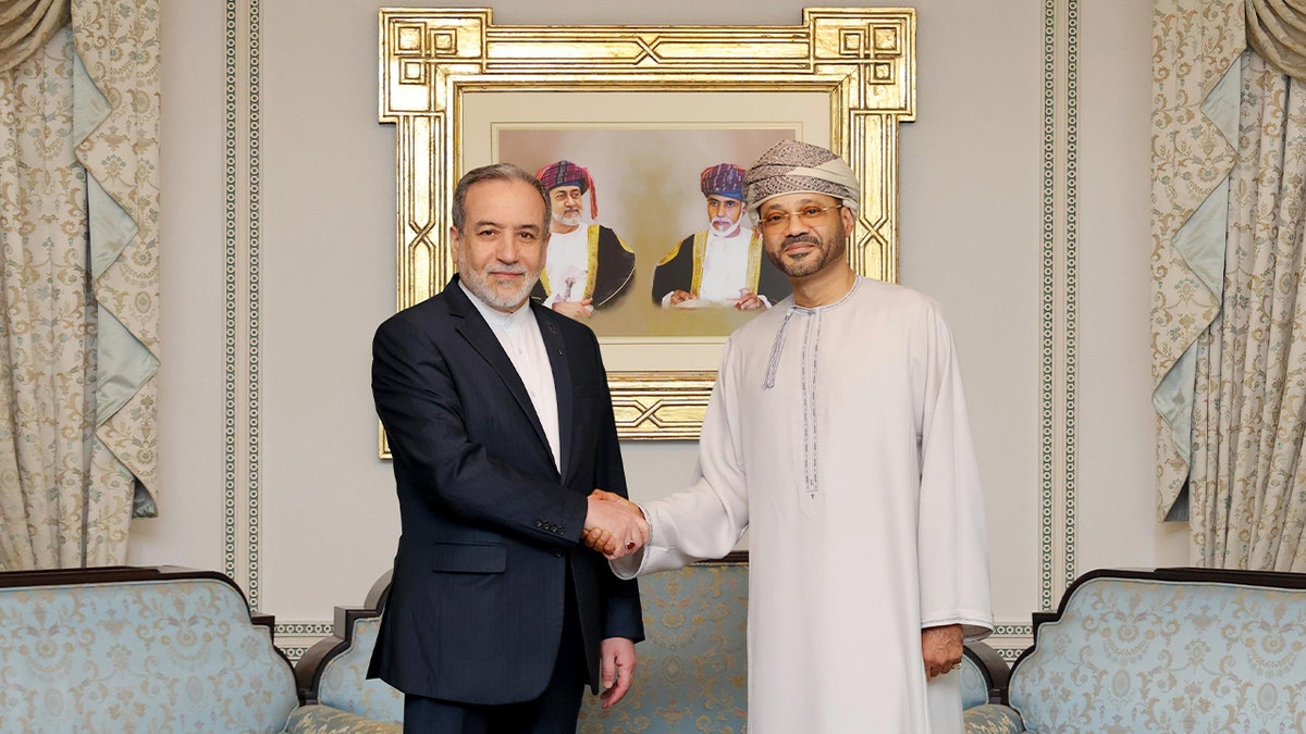 Two Middle Eastern diplomats shake hands during a formal meeting.