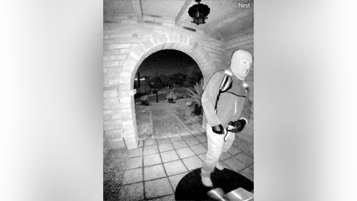 A view from a doorbell camera showing an armed individual outside the residence of Nancy Guthrie in Tucson, Arizona