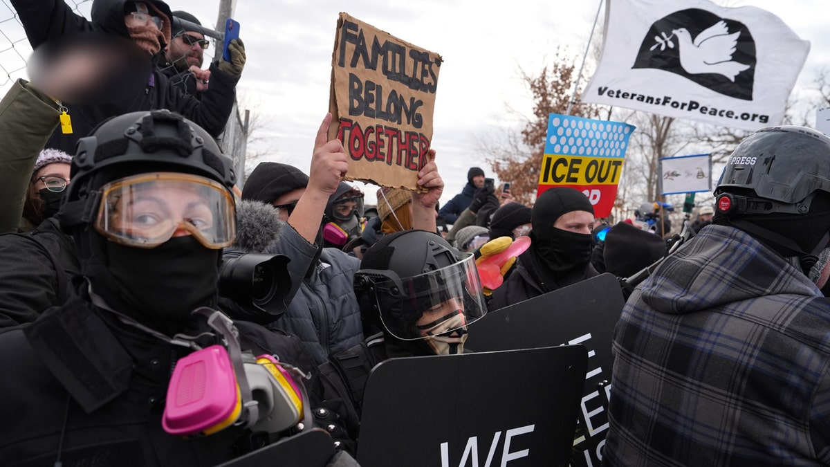 Protesters in riot gear holding signs