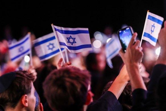 People wave Israeli flags at Thursday’s community event. 