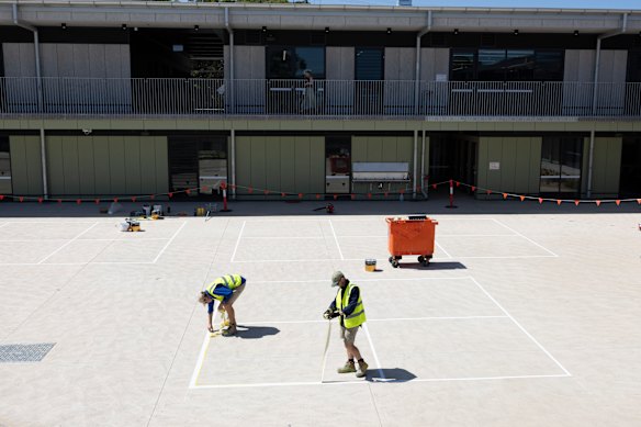 Workers painting lines for the school’s handball courts on Thursday.