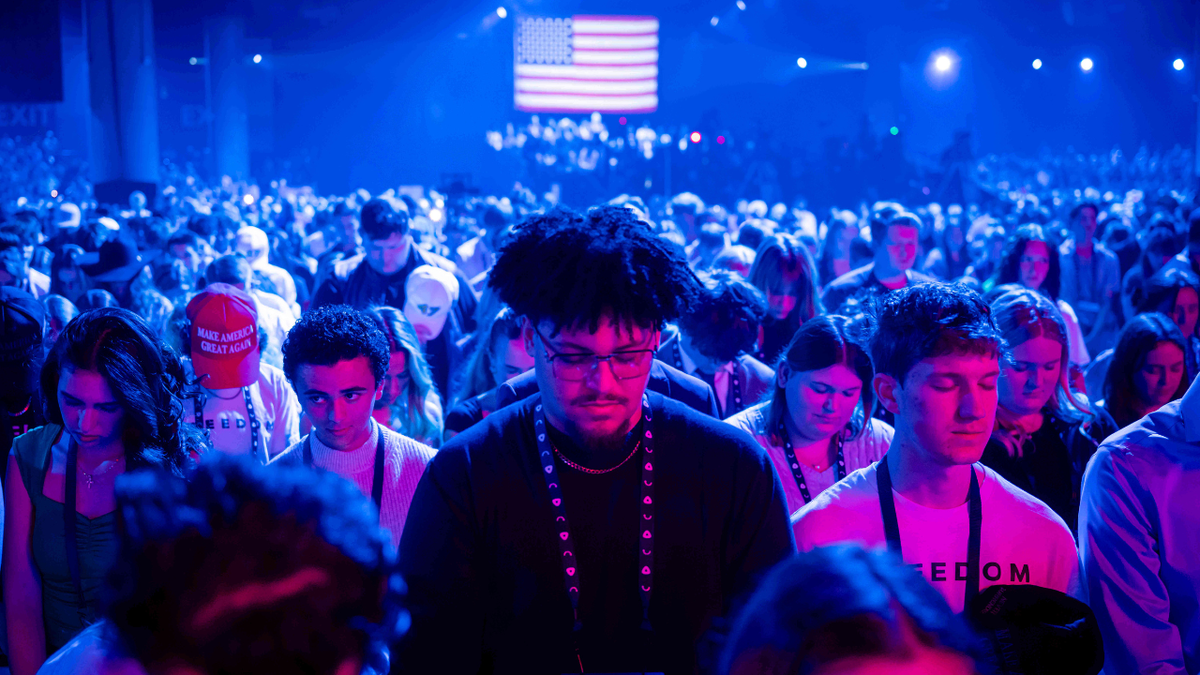 Attendees pray during Turning Point USA's AmericaFest 2025.