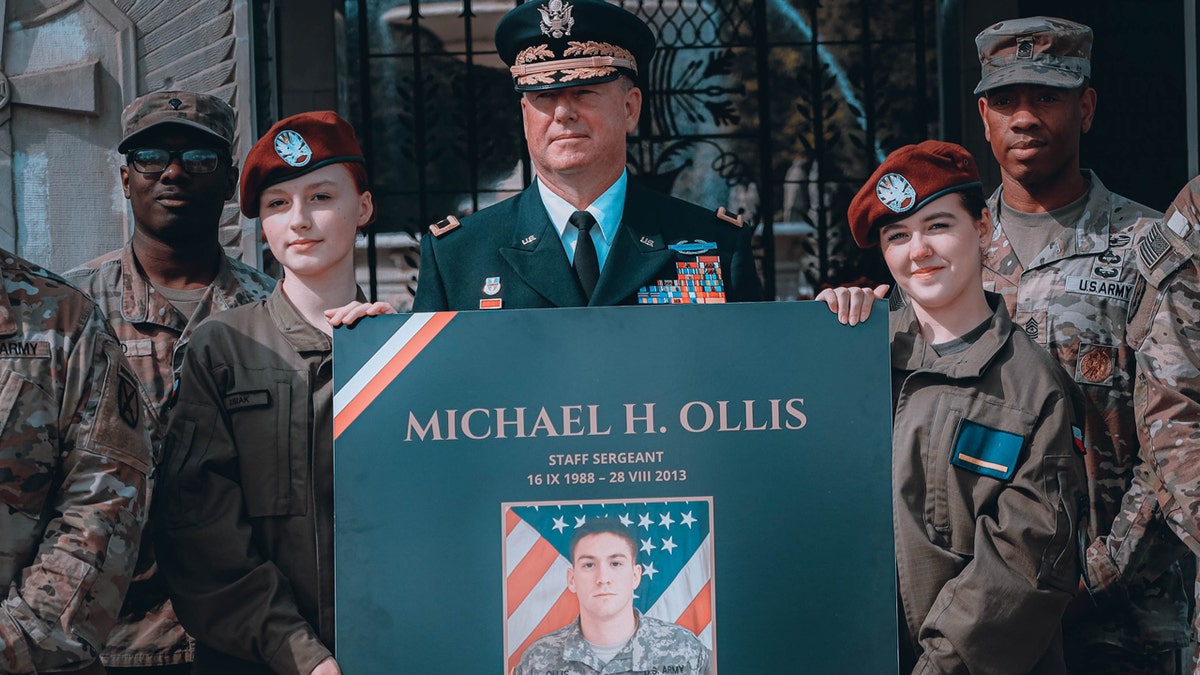 Brig. Gen. Eric Riley holds sign honoring Michael Ollis in Poland