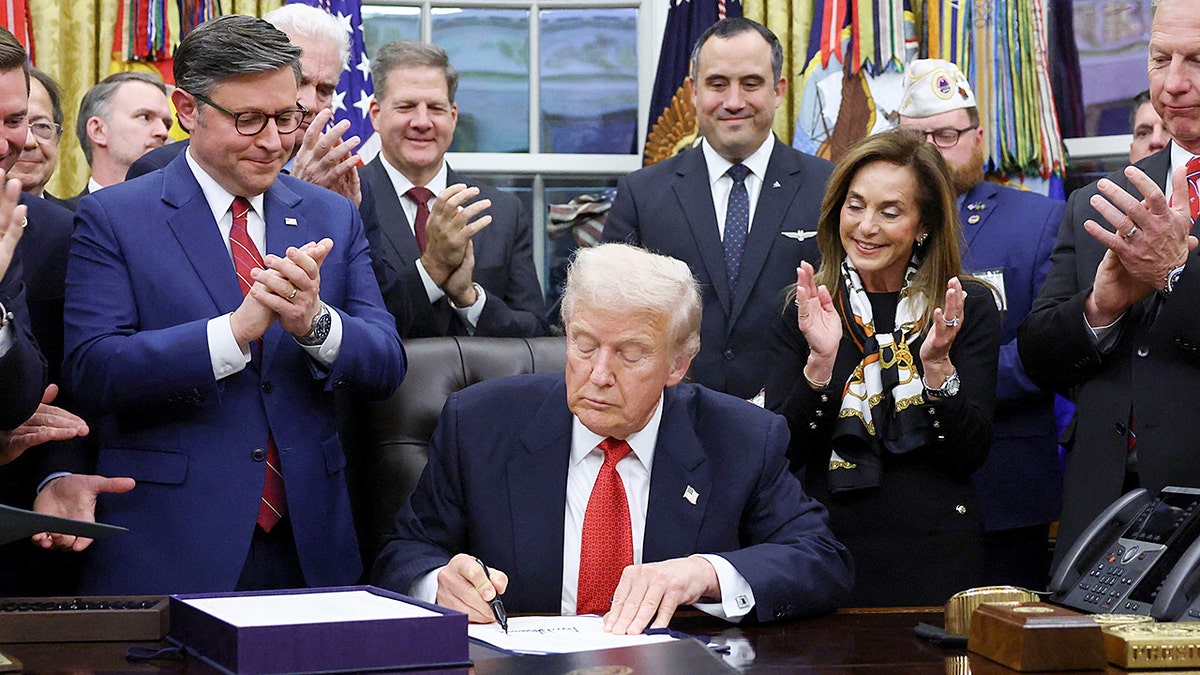 President Trump signs a bill into law surrounded by lawmakers