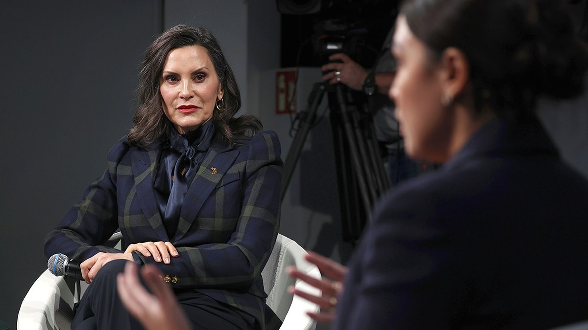 Gretchen Whitmer listens as Alexandria Ocasio-Cortez speaks at Munich conference.