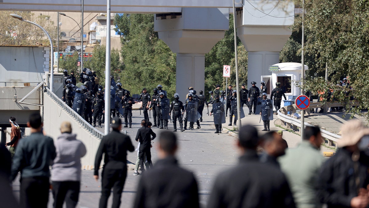 Protesters confront Iraqi security forces near a bridge amid unrest in Baghdad.