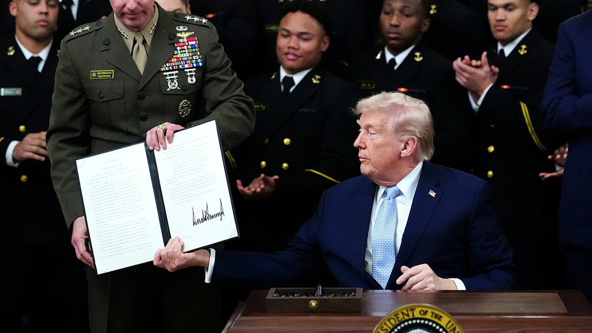 Donald Trump holds up a signed executive order