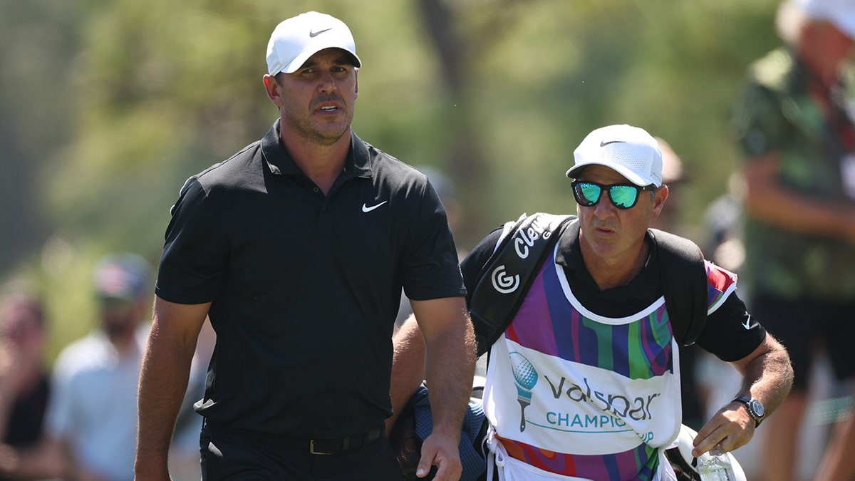 Brooks Koepka walks with caddy