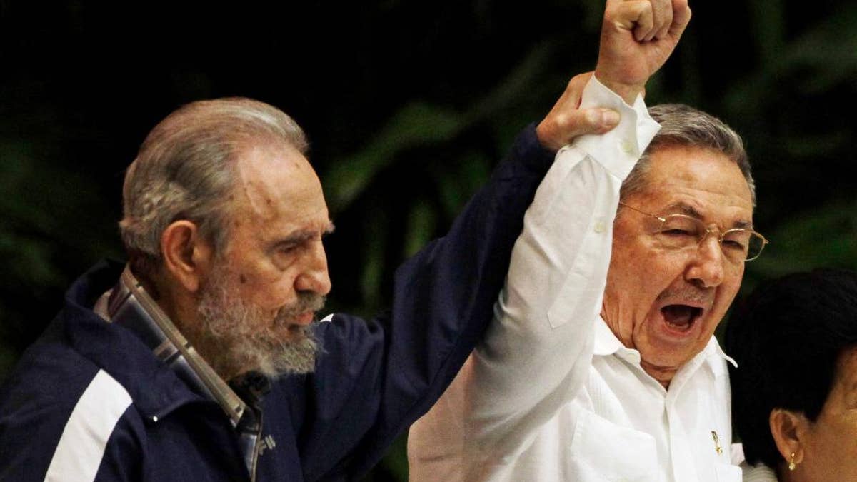 FILE - In this April 19, 2011 file photo, Fidel Castro, left, raises his brother's hand, Cuba's President Raul Castro, center, as they sing the anthem of international socialism during the 6th Communist Party Congress in Havana, Cuba. Cuban President Raul Castro has announced the death of his brother Fidel Castro at age 90 on Cuban state media on Friday, Nov. 25, 2016. (AP Photo/Javier Galeano, File)