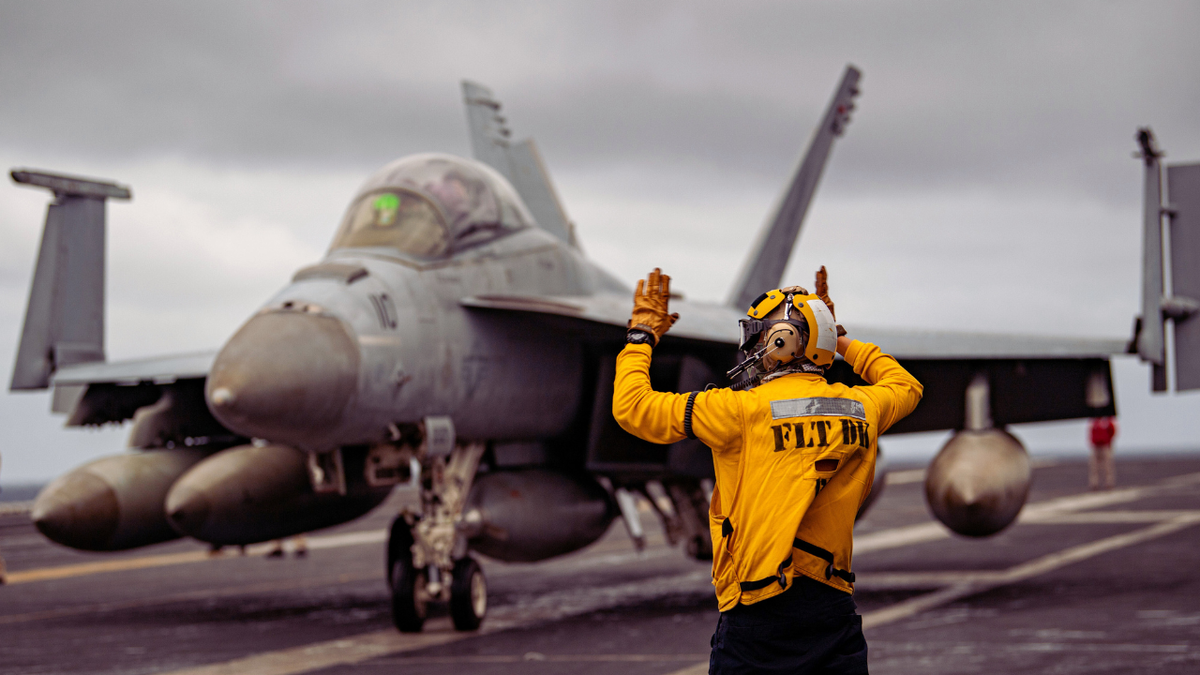 A U.S. Sailor directs an F/A-18F Super Hornet across the flight deck of the aircraft carrier USS Nimitz in the South China Sea, Nov. 5, 2025.