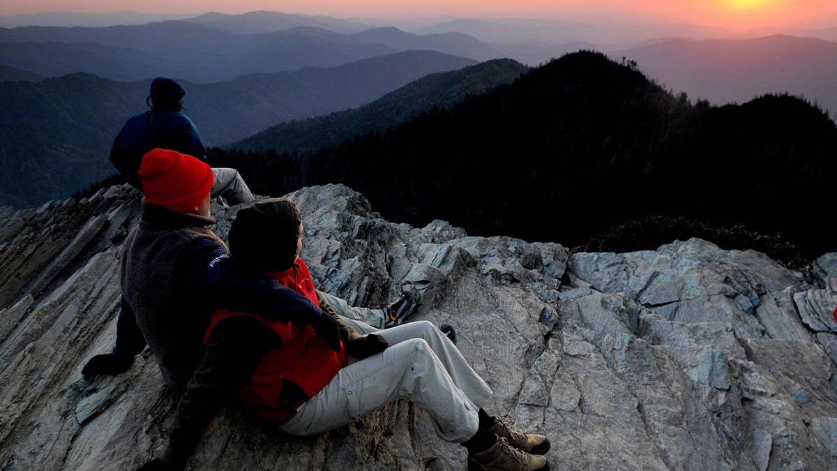 hikers sitting at summit during sunset