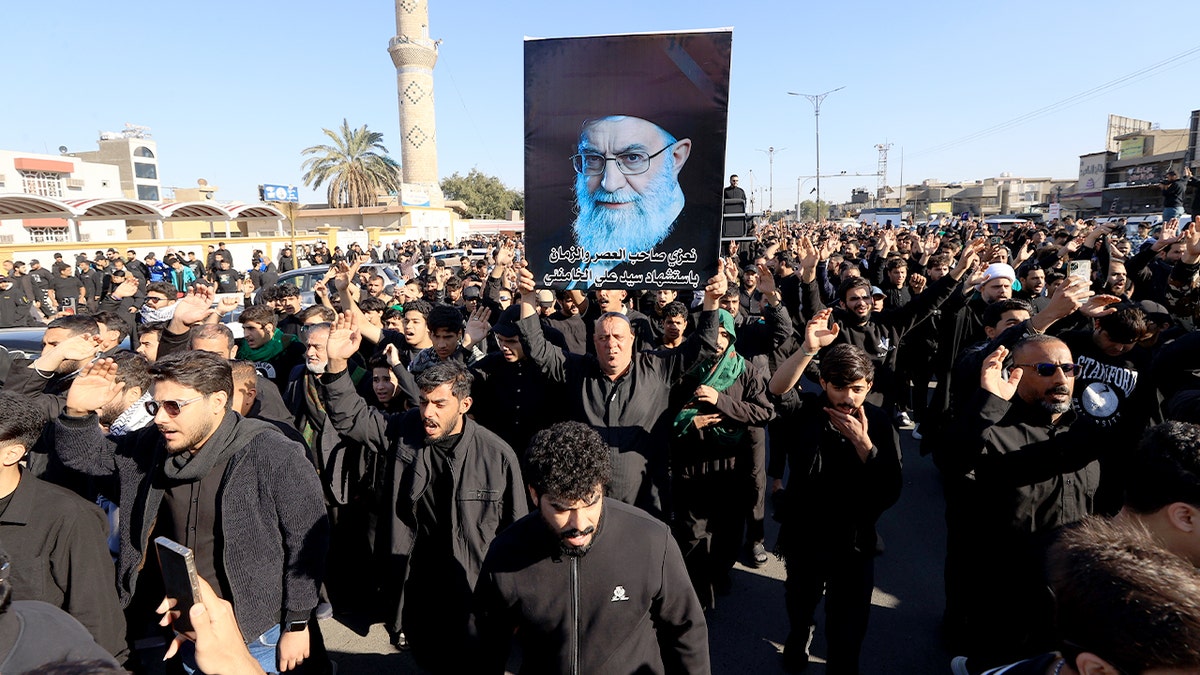 Demonstrators in Baghdad’s Sadr district wave Iranian flags and hold portraits of Iran’s supreme leader during a street protest.