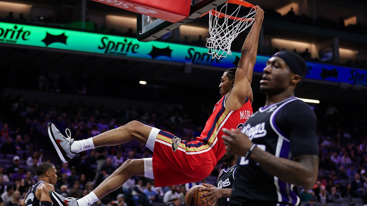 Trey Murphy III hangs on the rim after dunking the ball