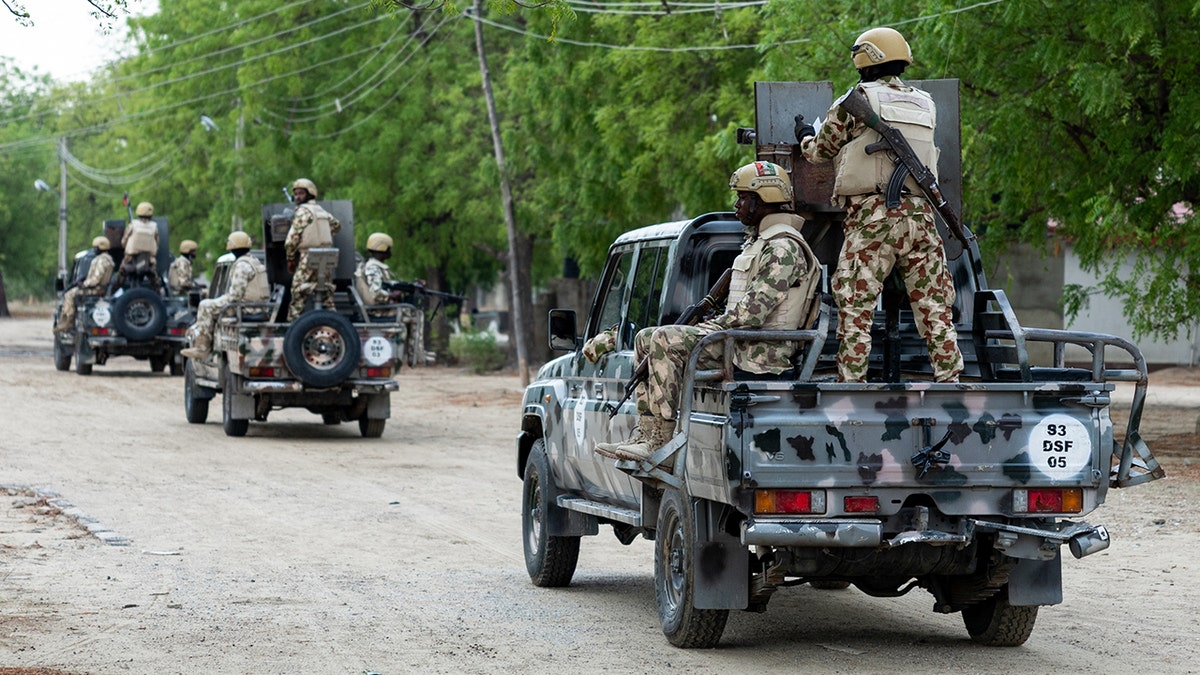 Nigerian soldiers ride with weapons in pick-up trucks