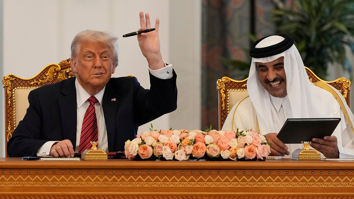 President Donald Trump waves alongside Qatari Emir al-Thani