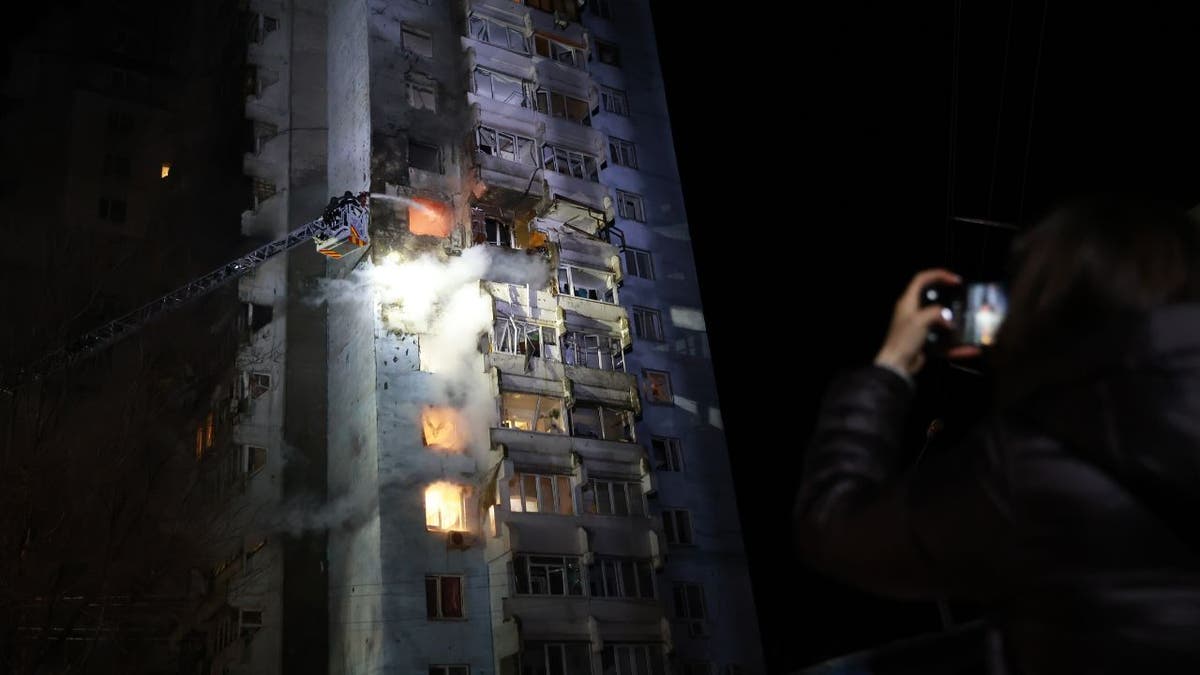 A residential high-rise burns after a Russian drone strike in Zaporizhzhia, Ukraine, as flames and smoke pour from multiple floors.