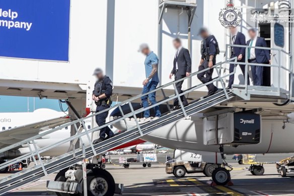 Ben Roberts-Smith is escorted off his flight by AFP officers upon arrival at Sydney Airport on Tuesday.