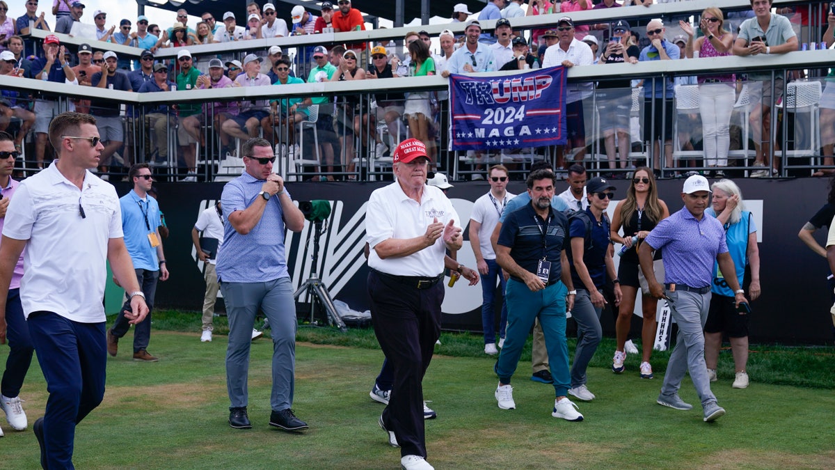Former President Donald Trump walking away from the first tee at a golf course.