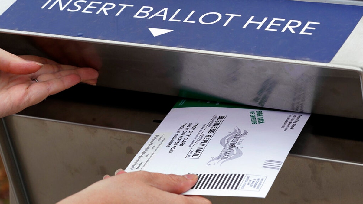 A Michigan voter inserting an absentee ballot into a drop box in Troy, Michigan