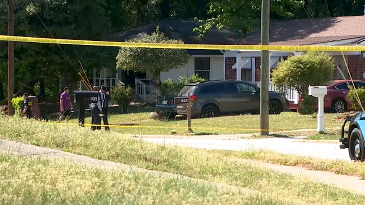 Police tape and investigators are seen in front of a house.