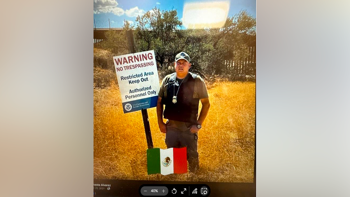 Man standing near U.S.-Mexico border sign reading 