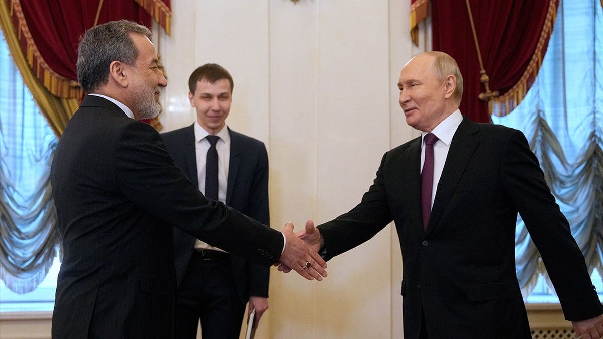 Russian President Vladimir Putin shakes hands with Iranian Foreign Minister Abbas Araqchi