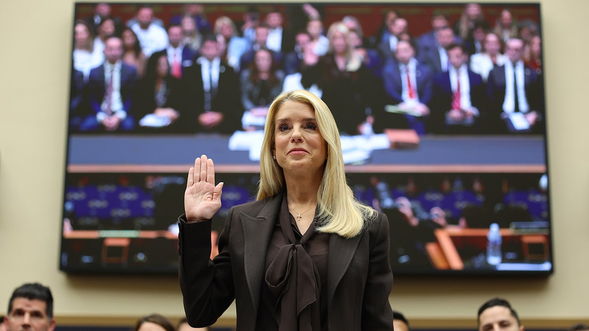 Attorney General Pam Bondi raising her right hand while being sworn in at a hearing on Capitol Hill.