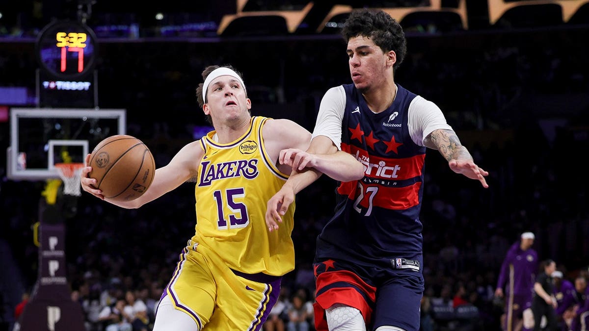 Los Angeles Lakers guard Austin Reaves driving against Washington Wizards guard Will Riley in a basketball game