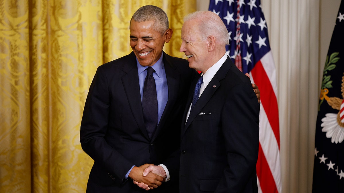 Former President Barack Obama and President Joe Biden shaking hands in the White House East Room