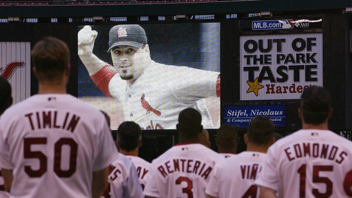 St. Louis Cardinals players standing on field watching video tribute to Darryl Kile