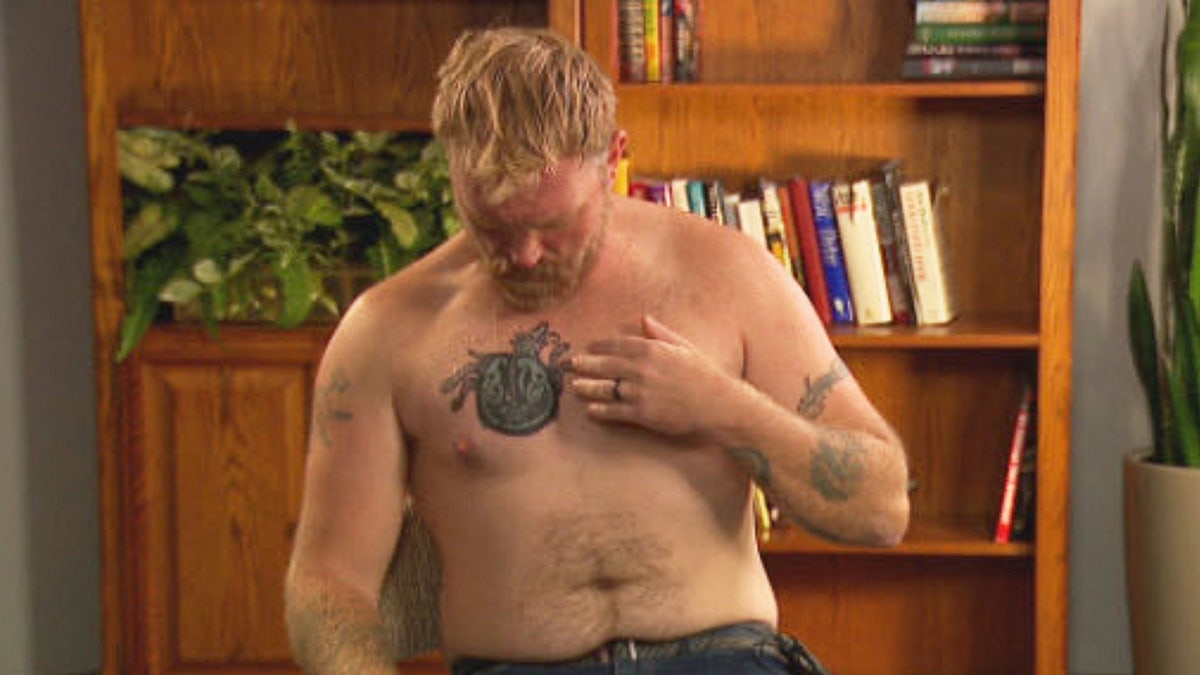 Graham Platner pointing to a covered tattoo on his arm during an interview in Portland, Maine