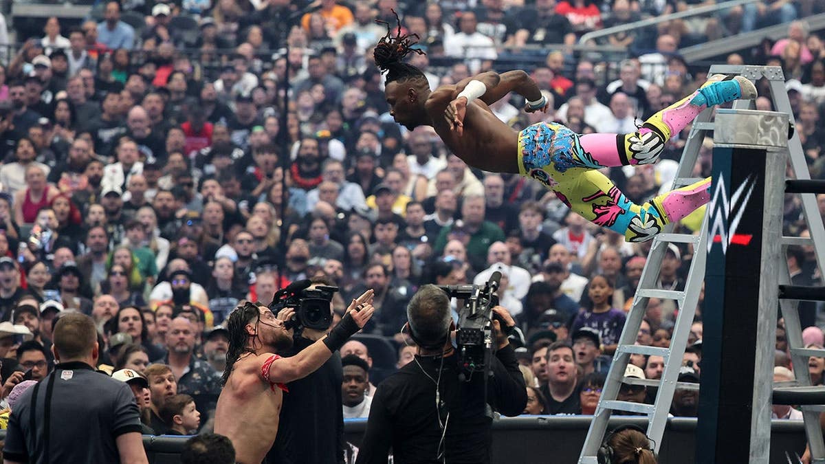 Je’Von Evans climbing over ropes in a wrestling ring during a ladder match